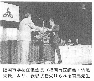 福岡市学校保健会長(福岡市医師会・竹嶋会長)より、表彰状を受けられる有馬先生